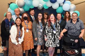A group shot of about 11 Curative Connections event volunteers underneath a balloon arch.
