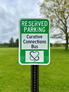 A road sign that says "Reserved Parking - Curative Connections Bus"