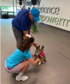 A man and young woman pet a cute looking dog