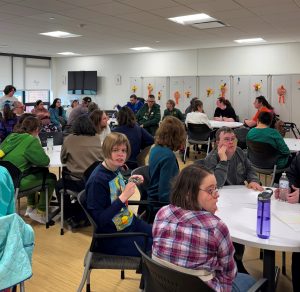 A room of Curative Connections participants play Trivial Pursuit at circular tables