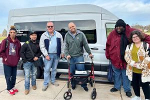 A group of 6 riders outside a Curative Connections van.