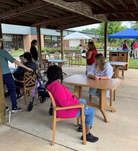 volunteers for the Curative Connections wheelchair wash gather around picnic tables underneath a pavilion